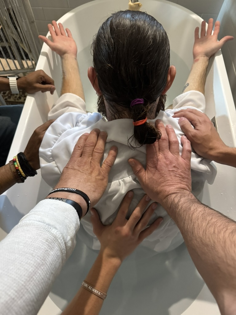 Hands praying over someone during water baptism