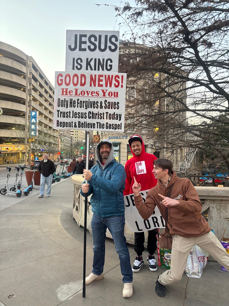 Street ministry with a Jesus is King good news sign